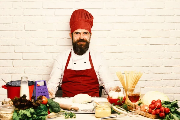 Man with beard by kneaded dough on white brick background