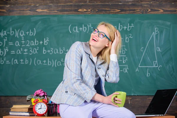 Machen Sie eine Minute Pause. Arbeitsbedingungen für Lehrer. Arbeitsbedingungen, die angehende Lehrer berücksichtigen müssen. Frau lächelnd Lehrer hält Becher trinken sitzen Tisch Klassenzimmer Kreidetafel Hintergrund — Stockfoto