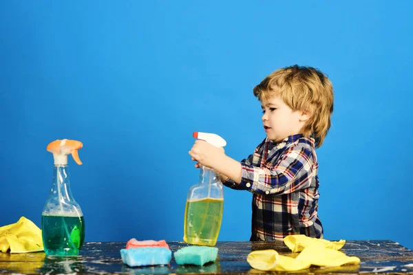 Kid with busy face holds spray on table. — Stock Photo, Image
