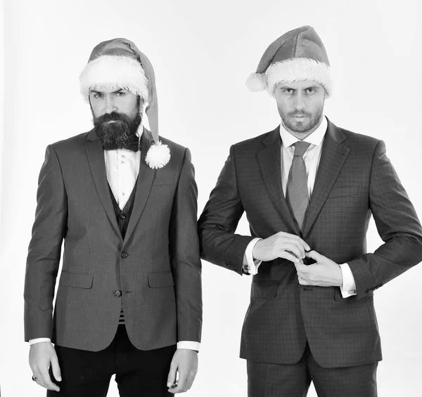 Men in smart suits and Santa hats on white background