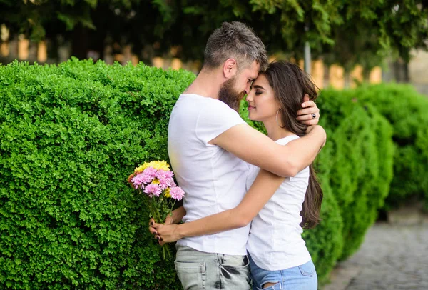 Man fall in love with gorgeous girl. Man bearded hipster hugs woman. Strong romantic feelings become true love. He will never let her go. Couple in love hugs on date in park green bushes background