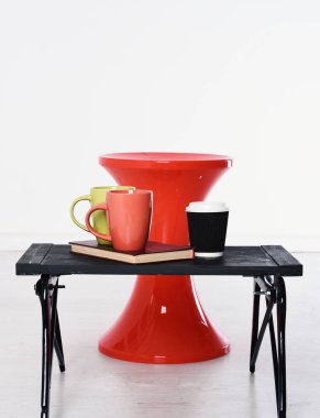 Kağıt bardak ve beyaz arka plan, kopya alanı üzerine bir kitap kırmızı sandalye ve kırmızı yeşil siyah ahşap tepsi.