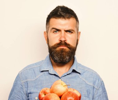 Sakallı adam beyaz arka planda kırmızı elmalar tutuyor..