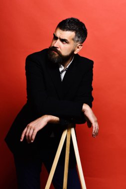 Sakallı ve bıyıklı adam klasik takım elbise giyiyor.