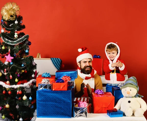 Weihnachtsfamilie öffnet Geschenke auf rotem Hintergrund — Stockfoto