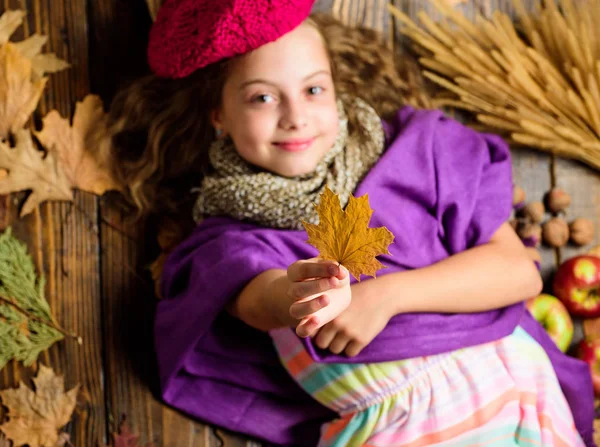 Kid flicka ljusa mjuk Stickad mössa beret. Höstens mode stickade tillbehör. Stickad mössa trend höstsäsongen. Flicka låg trä bakgrund sjunkit blad ovanifrån. Stickad tillbehör mode detalj — Stockfoto