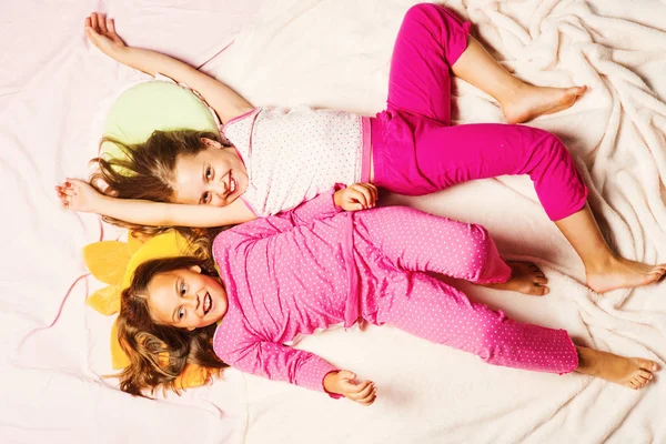 Barn med leende ansikten ligger på rosa bakgrund — Stockfoto