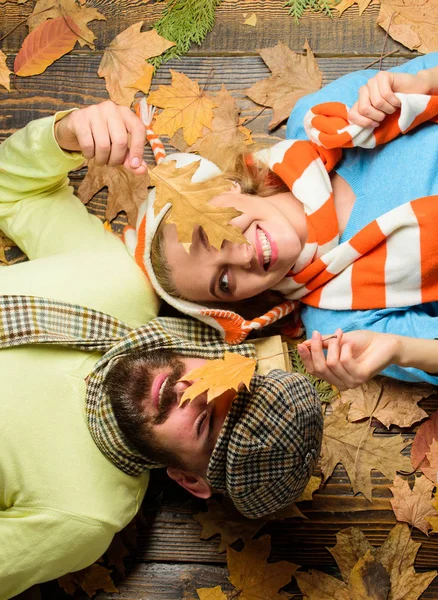 Fall date pleasant cozy atmosphere. Autumn date concept. Man bearded cheerful face and lady lay on wooden background with leaves top view. Couple in love in playful mood enjoy autumn cozy season