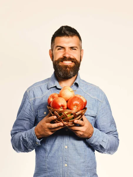 Farmer with happy face holds red apples.