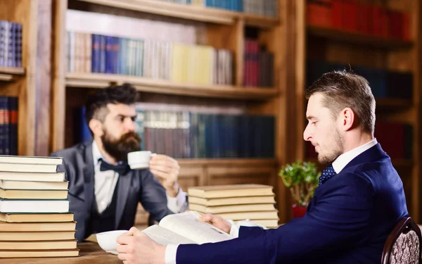 Meşgul yüzlü adamlar kitap okuyor, çalışıyor ve çay içiyor..