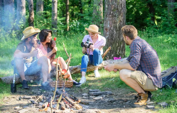 Company having hike picnic nature background. Tourists sharing thoughts about hike sit on log. Picnic with friends in forest near bonfire. Hikers sharing impression of walk forest. Summer tradition — Stock Photo, Image