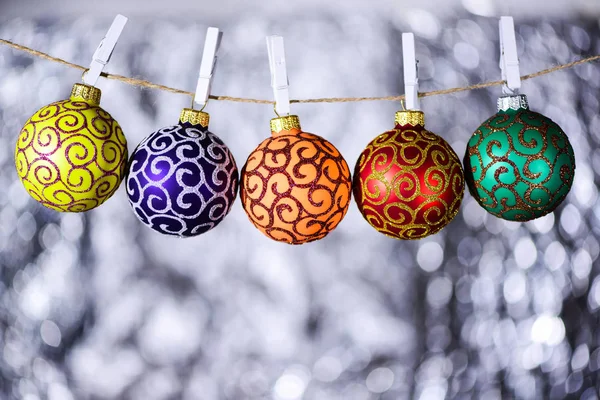 Christmas ornaments concept. Balls with ornaments hang on twine with clothes pins. Twine with pinned by clothes pins christmas ornaments, white background, defocused — Stock Photo, Image