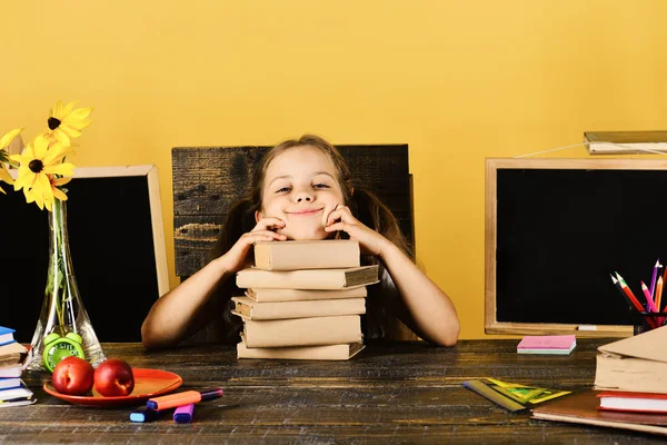 Школьница со счастливым и смешным выражением лица лежит на книгах — стоковое фото