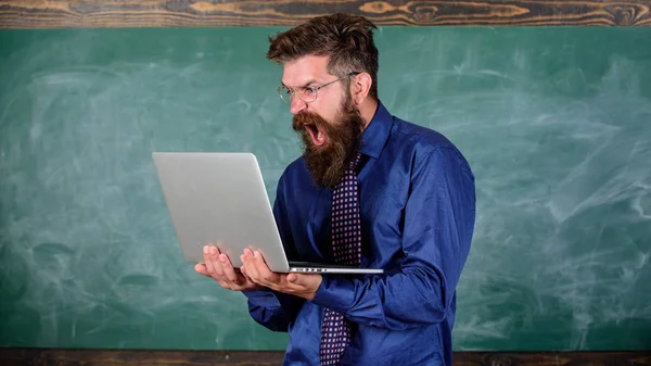 Annoyed by slow internet. Slowly internet annoying him. Teacher bearded man modern laptop chalkboard background. Hipster teacher aggressive with laptop goes mad about slow speed internet connection — Stock Photo, Image