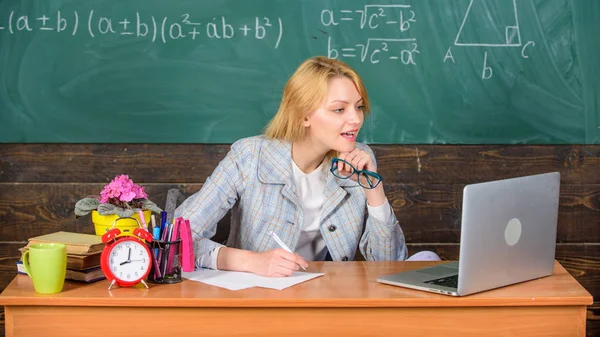 Wanita guru duduk meja kerja laptop berselancar latar belakang papan tulis internet. Mengatur kelas dan membuat proses belajar mudah. Pelajaran saat ini secara komprehensif menggunakan visual untuk memfasilitasi pembelajaran — Stok Foto