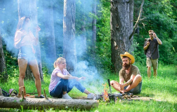 Ci riuniamo per un bel picnic. La compagnia si diverte mentre arrostisce salsicce su bastoncini. Amici incontro a prato per appendere fuori e preparare salsicce arrosto snack sfondo natura. Iscriviti picnic estivo — Foto Stock