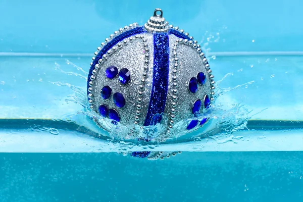 Svátky a dovolené koncepce. Vánoční dekorace nebo hračka pro vánoční stromeček zaplavat v bazénu. Slavnostní dekorace pro vánoční stromeček, modrý míč spadl do vody s pozadím postříkání, modré — Stock fotografie