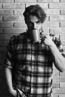 Duvarda fincanı tutan yakışıklı adam.