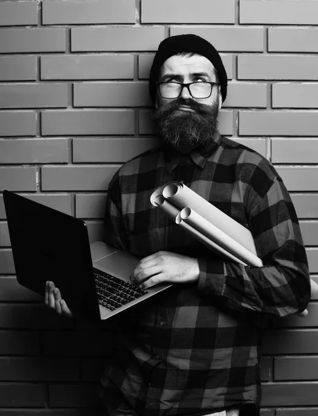 stock image Bearded brutal caucasian hipster holding laptop and craft paper