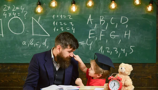担任の先生の息子は、小さな男の子、ひげの父します。子供の注意欠陥を勉強しながら陽気な気が散る。いたずらっ子のコンセプトです。教師と鏝板、背景に黒板に生徒 — ストック写真