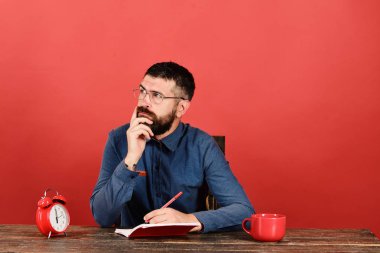 Düşünen yüzlü adam ahşap masada oturur.
