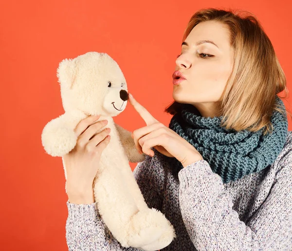 Woman holds teddy bear playing with his nose on red