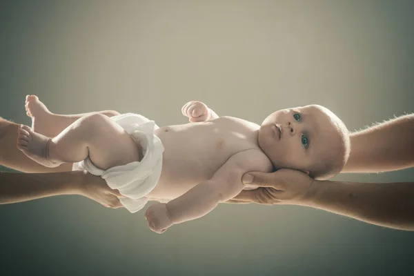 Младенец, держащийся руками обоих родителей на сером фоне . — стоковое фото