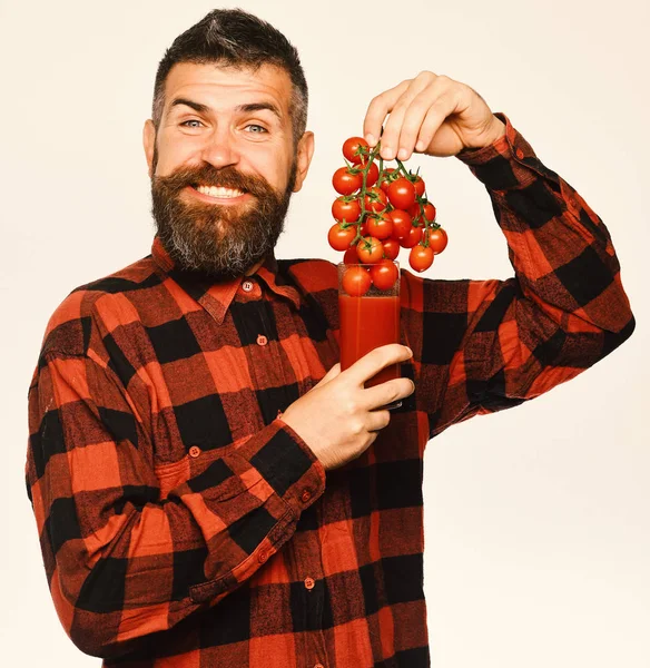 収穫の男だ 笑顔の農家は チェリートマトで作られた新鮮なジュースを提供しています ひげを生やした男は白い背景に隔離されたトマトジュースのガラスに果実を置く 農業と秋のコンセプト — ストック写真