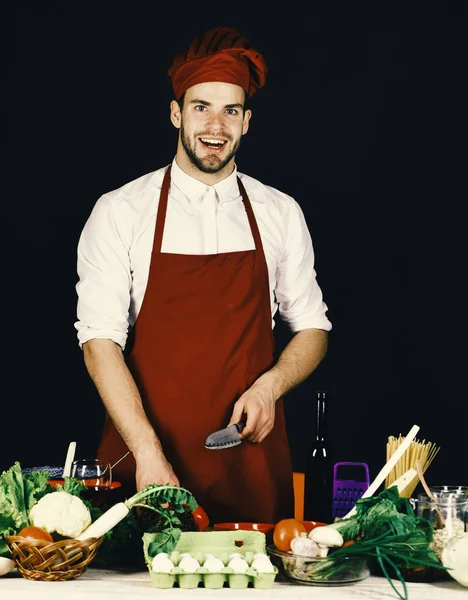Hombre con sombrero y delantal, chuletas de pimienta. Concepto de comida vegetariana — Foto de Stock