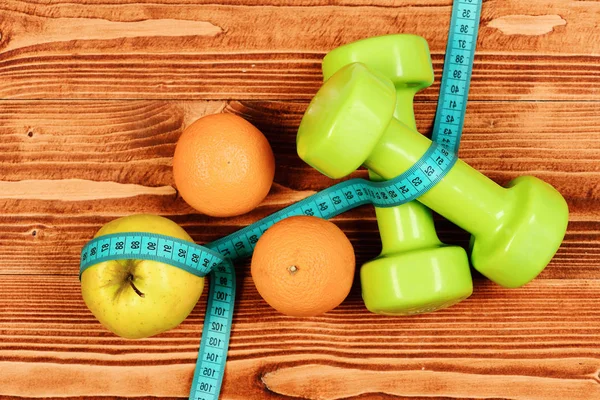 Weight dumbbells with measuring tape, apple, orange for diet concept — Stock Photo, Image