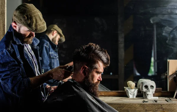 Barber with clipper styling hair of brutal bearded client. Hipster lifestyle concept. Hipster client getting haircut. Barber with hair clipper works on hairstyle for bearded man barbershop background — Stock Photo, Image