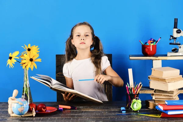 Estudante senta-se na mesa com rosto sério detém livro — Fotografia de Stock