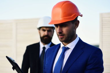 Planı ya da bütçeyi tartışan inşaatçılar. Eş çalışma ve inşaat kavramı.