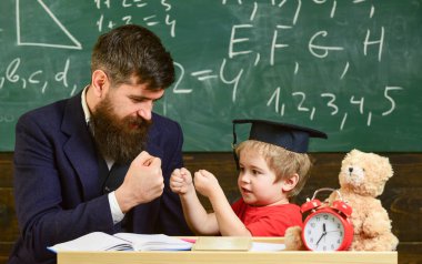 Neşeli boks baba yenerek, evlat. Öğretmen ve öğrenci kolej, kara tahta arka plan içinde. Oynak çocuk kavramı. Baba sakallı, evlat, öğretmen öğretir küçük çocuk, çocuk onu yenerek iken