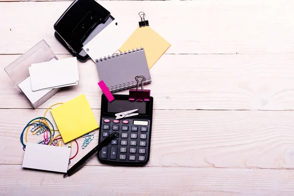 Notebook e puncher vicino penna su sfondo di legno bianco . — Foto Stock