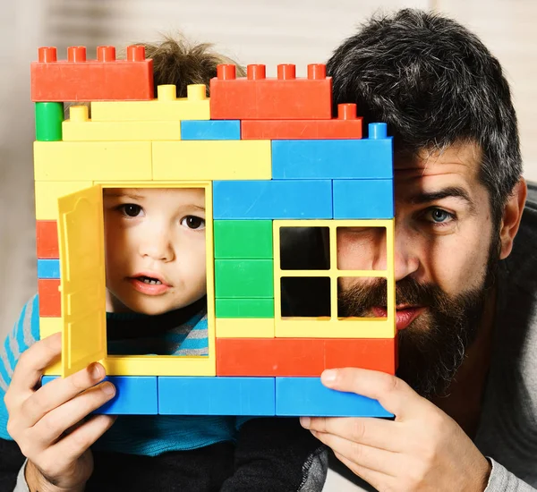 Pai e filho com rostos preocupados por trás de tijolos coloridos construção — Fotografia de Stock