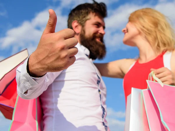 Couple in love recommend shopping summer. Happy wife satisfied purchases. He knows how to make her happy. Couple with shopping bags cuddle blue sky background. Man with beard shows thumb up gesture