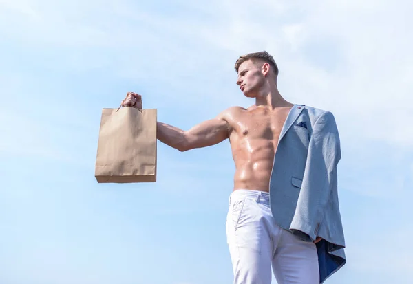 魅力的なマッチョの男は、茶色の紙で作った買い物袋を運ぶ。このパッケージを取る。販売シーズンです。エコ健康製品。男の筋肉アスリート ショッピング バッグ空背景を保持します。ホット販売と割引 — ストック写真