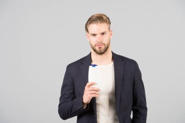 Kepek ortak erkek sorun. İlaçlar kepek kurtulmak. Resmi takım elbise şişe şampuan gri arka plan tutun. Kaşıntılı kafa derisi ve flakiness cilt. Şampuan kepek sorunu çözmek. Kepek şampuanı Anti