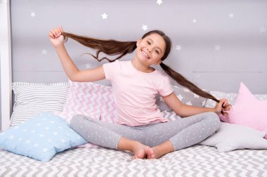 Kız çocuk yatak yatak odasında oturmak. Çocuk saç yatağına git önce hazırlayın. Kız çocuk uzun saç sevimli pijama rahatlatıcı yatak odasında. Uyku veya şekerleme vakti. Uzun saç isteğe bağlı özel bakım ve günlük penye