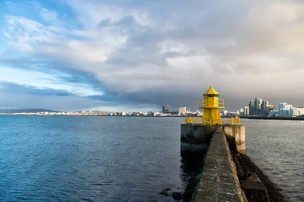 Sea port navigation concept. Sea transportation and navigation. Lighthouse on sea pier in reykjavik iceland. Lighthouse yellow bright tower at sea shore. Seascape and skyline with bright lighthouse