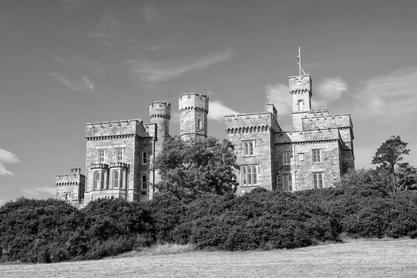 Lews Castle on blue sky in Stornoway, UK. Замок с зелеными деревьями на природном ландшафте. Викторианский стиль архитектуры и дизайна. Ориентир и достопримечательность. Летние каникулы и похоть — стоковое фото