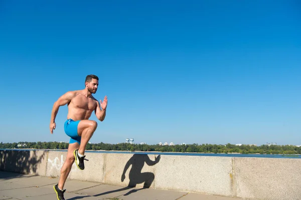 Mannen idrottsman muskulös överkropp träning utomhus. Morgon kör fyllningar med energi. Löpare träning morgon under sunrise. Motivation och prestation. Kör morgon vana. Löpare rörelse framåt himmel bakgrund — Stockfoto