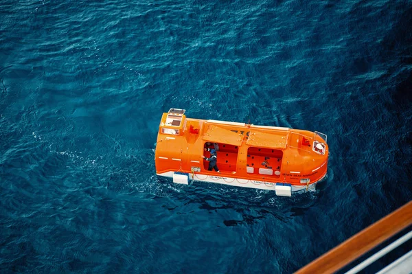 Πορτοκαλί διάσωσης, σωσίβια λέμβο για εκκένωση έκτακτης ανάγκης με ανθρώπους στο νερό — Φωτογραφία Αρχείου