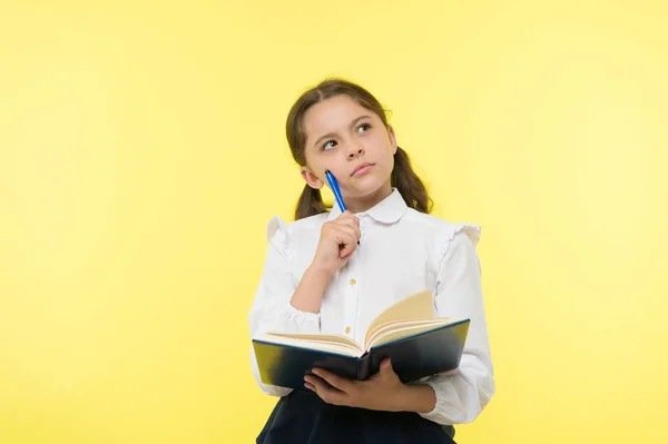 Chica linda colegiala en uniforme mantenga libro o libro de texto de fondo amarillo. Alumno diligente obtener conocimiento del libro. Los niños usan uniforme escolar preparan para la lección sus conocimientos. Conocimiento complejo — Foto de Stock