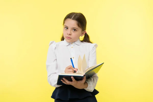 女孩可爱的女生在制服举行书与信息黄色背景 学生从书中获取信息 儿童穿校服准备上课信息 注意信息 — 图库照片