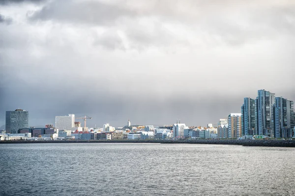 Reykjavik paisagem marinha céu nublado dramático. Cidade na costa marítima Islândia. Conceito de paisagem marinha escandinava. Superfície de água calma e cidade com edifícios altos arquitetura moderna. Cidade escandinava à beira-mar — Fotografia de Stock