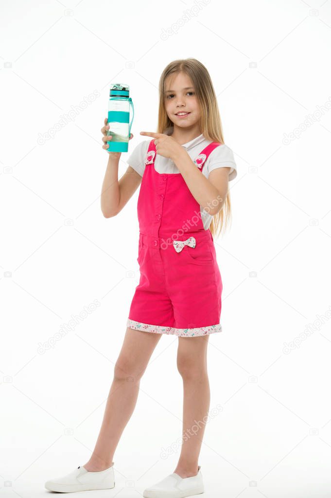 Stay hydrated. Girl cares about health and water balance. Girl on smiling face posing with water bottle isolated white background. Kid girl long hair pointing at water bottle. Water balance concept