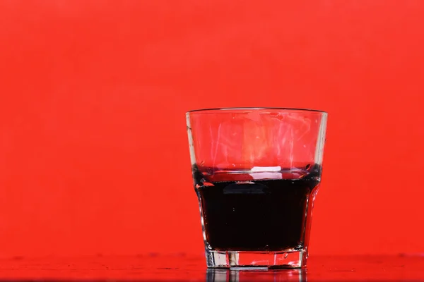 Beber en vaso de whisky sobre fondo rojo, copiar spac — Foto de Stock