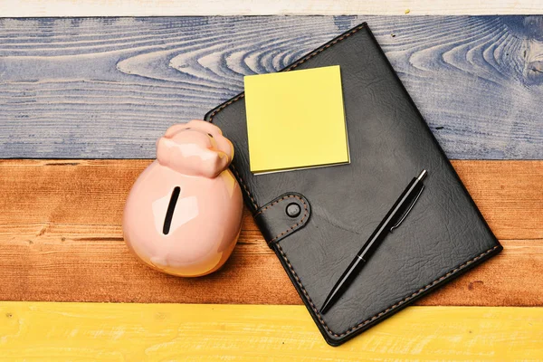 Moneybox with pig face near organizer and pen.